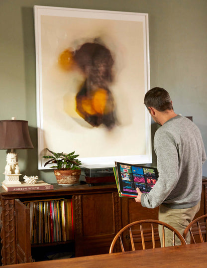 Floral Movements print hanging on a wall above a table with a person looking at records